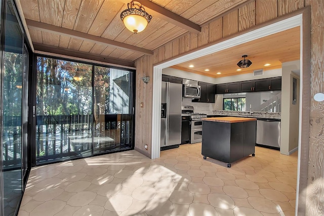 kitchen featuring beam ceiling, a center island, wooden counters, backsplash, and appliances with stainless steel finishes