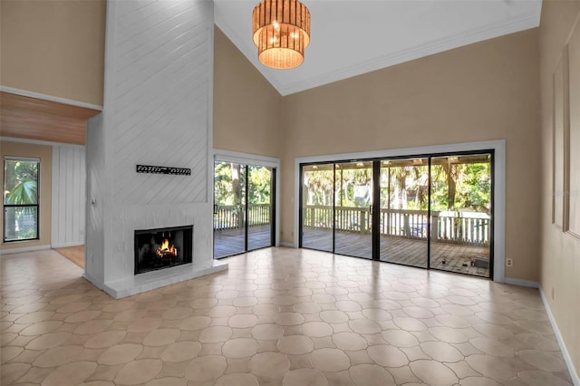 unfurnished living room featuring a high ceiling, a large fireplace, an inviting chandelier, and a wealth of natural light