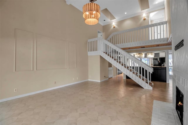 unfurnished living room with a towering ceiling, ornamental molding, and an inviting chandelier