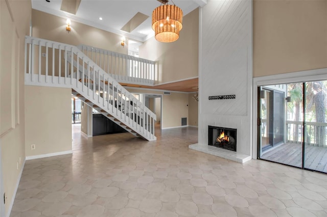 unfurnished living room with a high ceiling, a large fireplace, and a notable chandelier