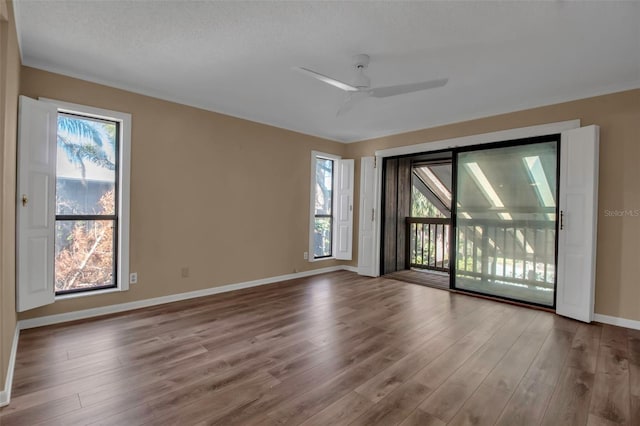 spare room featuring a wealth of natural light, light hardwood / wood-style flooring, ceiling fan, and a textured ceiling