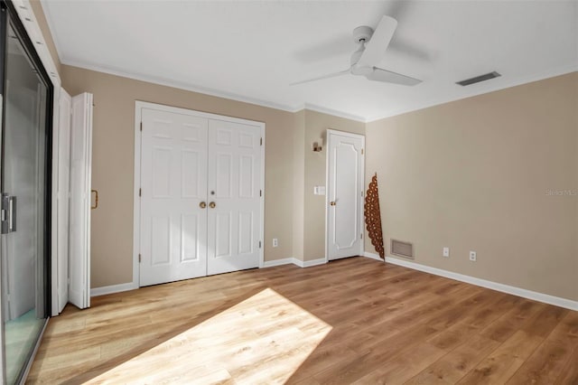 unfurnished bedroom featuring hardwood / wood-style flooring, ceiling fan, ornamental molding, and two closets