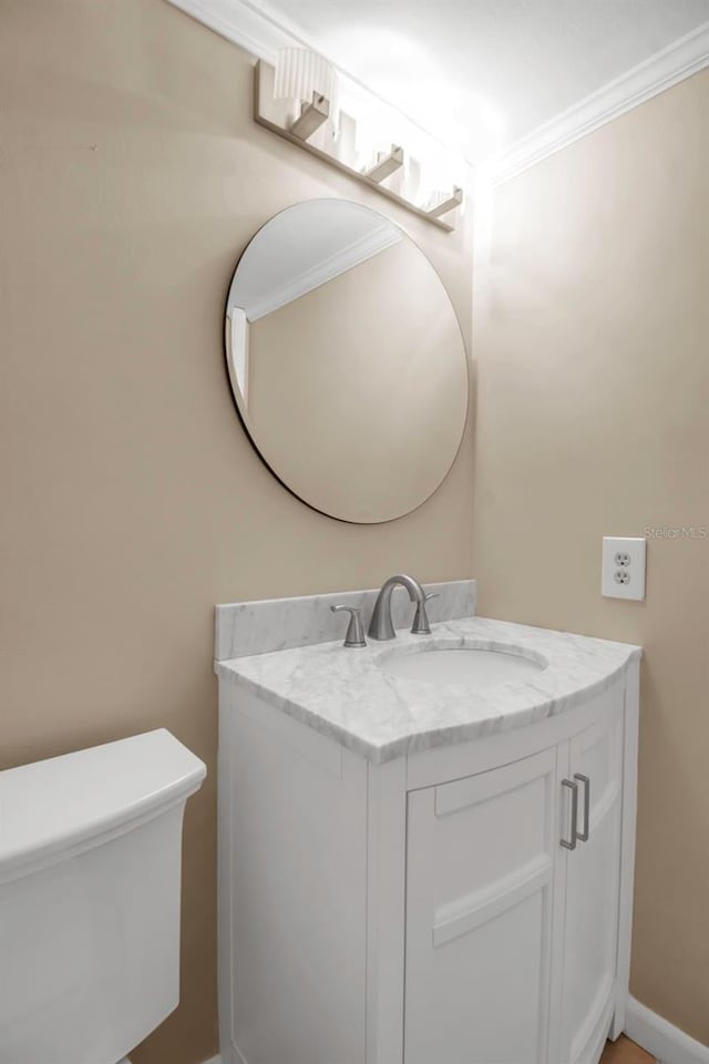 bathroom with vanity, toilet, and crown molding