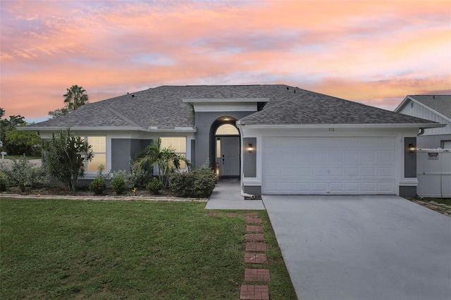 single story home featuring a garage and a yard