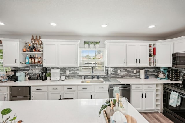 kitchen featuring appliances with stainless steel finishes, backsplash, sink, light hardwood / wood-style floors, and white cabinetry