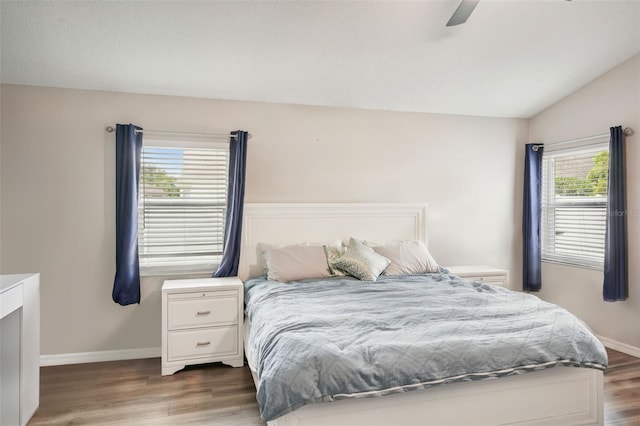 bedroom featuring ceiling fan, lofted ceiling, wood-type flooring, and multiple windows