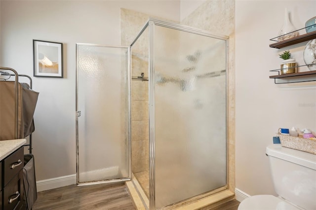 bathroom with vanity, toilet, wood-type flooring, and a shower with door