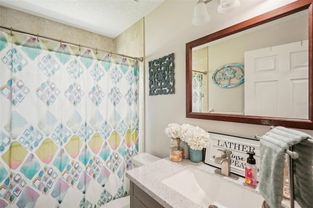 bathroom with vanity, toilet, a textured ceiling, and walk in shower