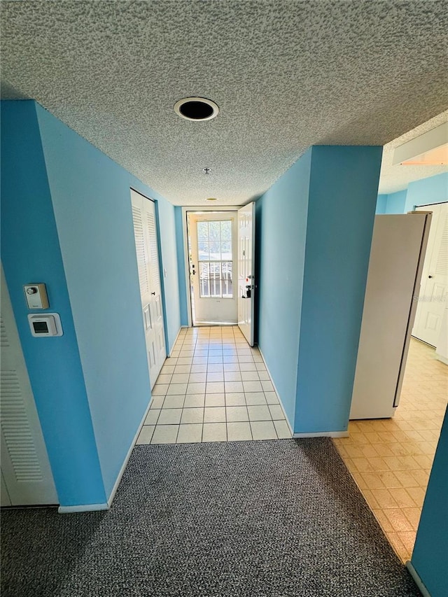 hall with light tile patterned floors and a textured ceiling