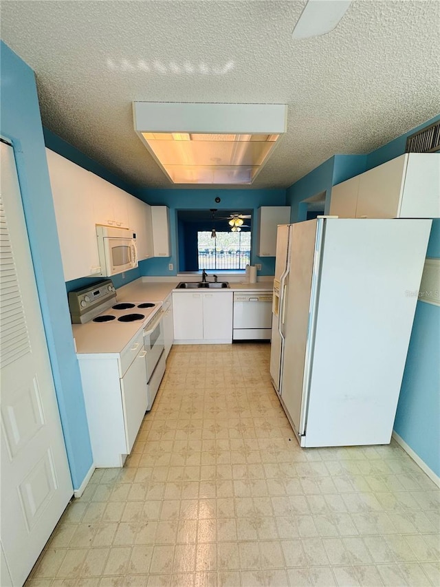 kitchen with white appliances, white cabinets, sink, a skylight, and a textured ceiling