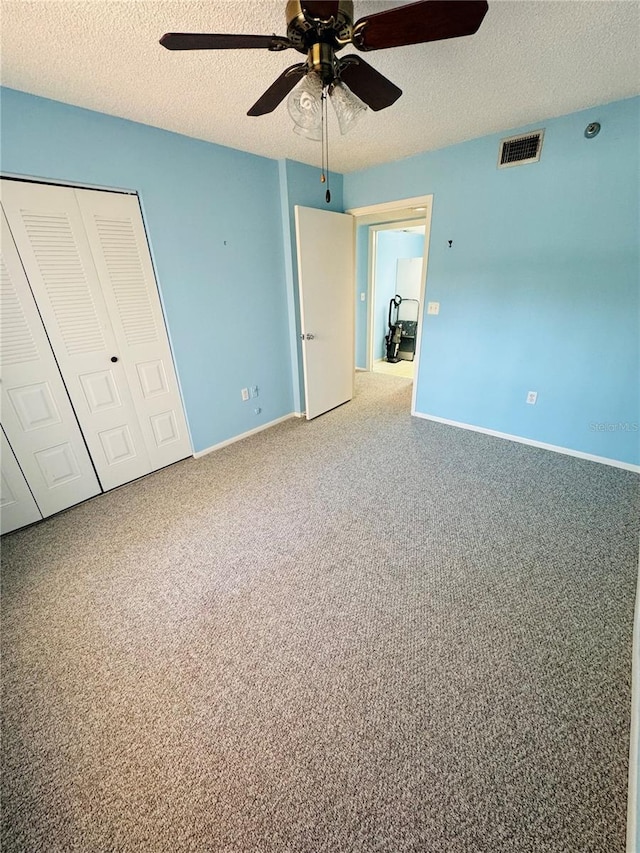 unfurnished bedroom featuring ceiling fan, a closet, carpet floors, and a textured ceiling