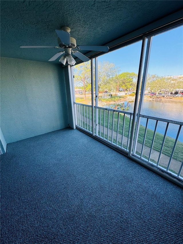 unfurnished sunroom featuring ceiling fan and a water view