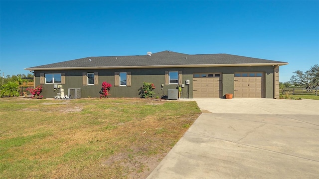 view of front facade with a garage, a front yard, and central air condition unit