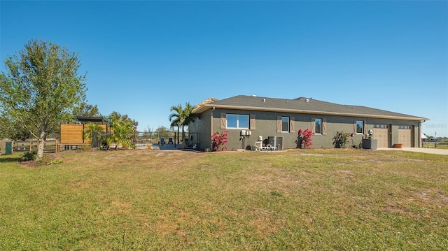 rear view of house featuring a garage, cooling unit, and a lawn