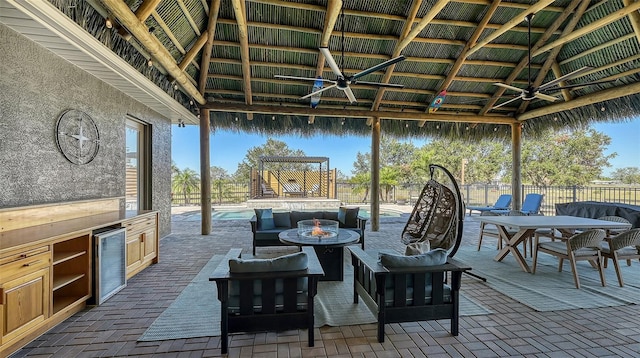 view of patio featuring a gazebo, area for grilling, ceiling fan, beverage cooler, and an outdoor living space with a fire pit