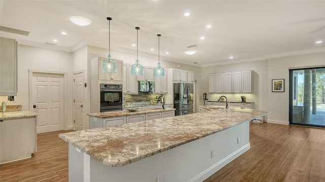 kitchen with decorative light fixtures, sink, a large island, light stone counters, and black appliances