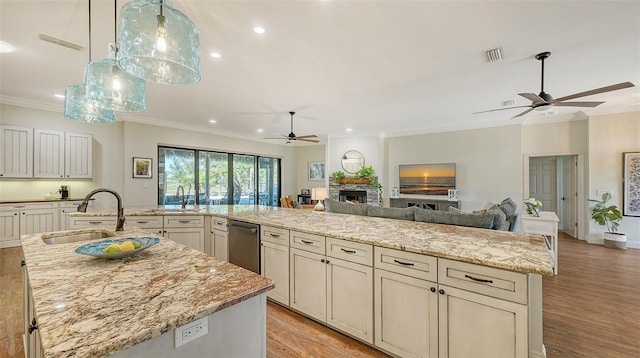 kitchen featuring sink, ornamental molding, light stone countertops, light wood-type flooring, and a spacious island