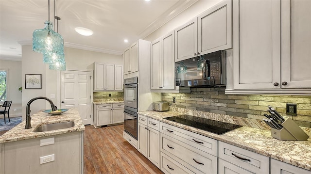 kitchen featuring pendant lighting, sink, ornamental molding, black appliances, and light stone countertops