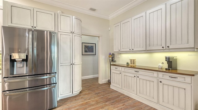 kitchen featuring stainless steel refrigerator with ice dispenser, white cabinetry, crown molding, wooden counters, and light wood-type flooring