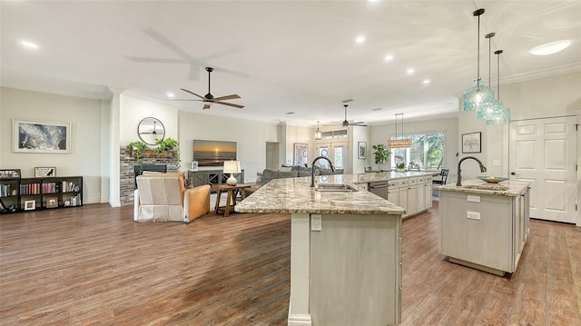 kitchen featuring light stone counters, decorative light fixtures, sink, and a center island with sink