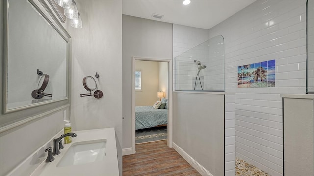 bathroom with wood-type flooring, vanity, and a tile shower