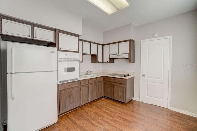 kitchen with white appliances, light hardwood / wood-style flooring, and sink