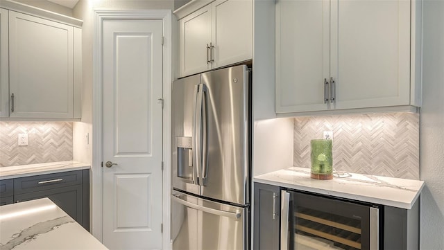 kitchen with stainless steel fridge, backsplash, gray cabinets, and wine cooler