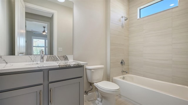 full bathroom featuring vanity, tiled shower / bath combo, toilet, and ceiling fan