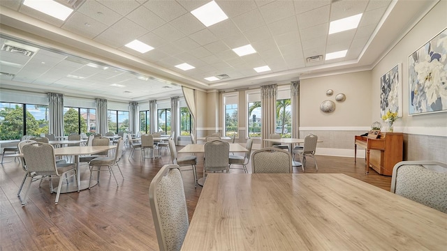 dining room featuring wood-type flooring, a paneled ceiling, and a healthy amount of sunlight