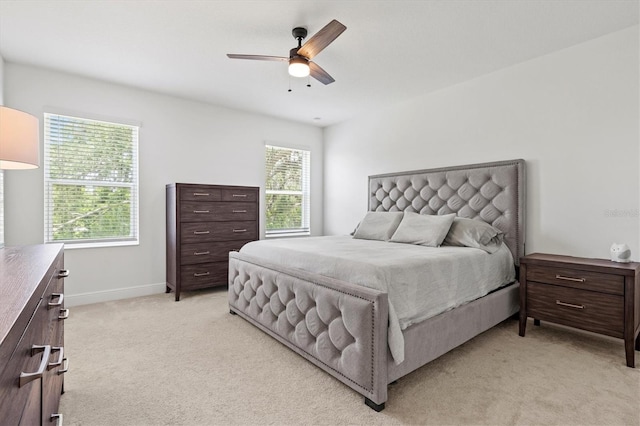 bedroom with ceiling fan, light carpet, and multiple windows