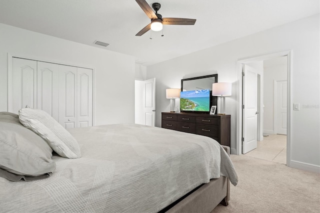 bedroom with a closet, ceiling fan, and light colored carpet