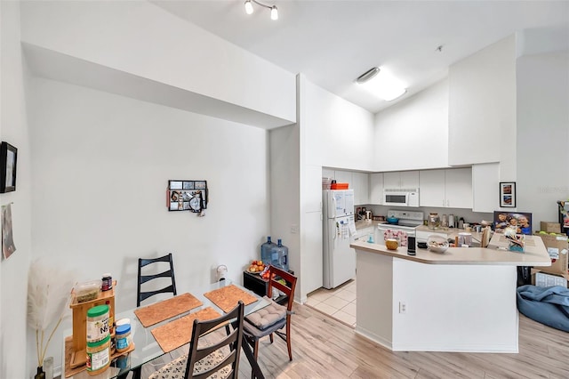 kitchen featuring kitchen peninsula, white appliances, white cabinets, a high ceiling, and light hardwood / wood-style floors