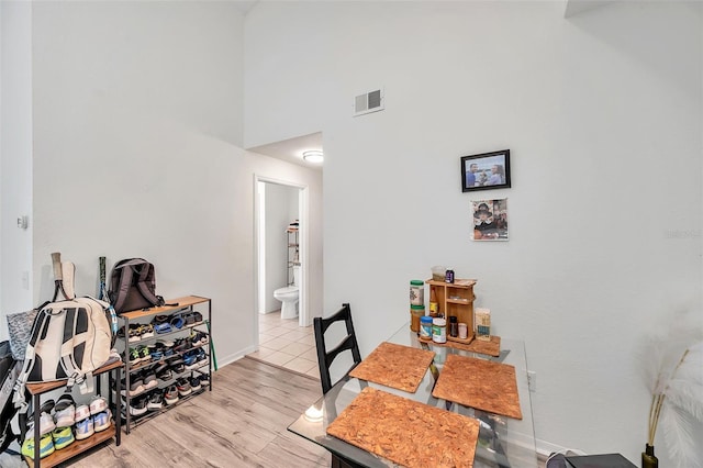 dining area featuring a towering ceiling and light hardwood / wood-style floors