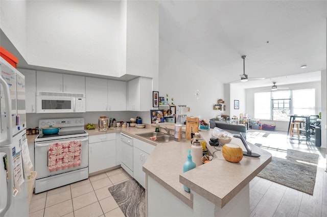 kitchen with white appliances, sink, ceiling fan, light wood-type flooring, and kitchen peninsula