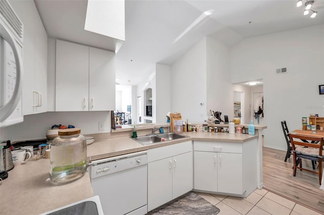 kitchen with white dishwasher, white cabinets, sink, light hardwood / wood-style floors, and kitchen peninsula