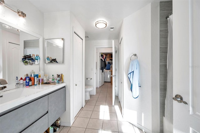 bathroom with toilet, vanity, and tile patterned floors