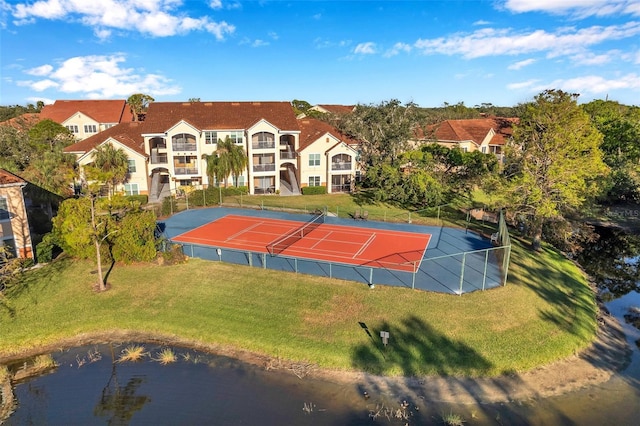 exterior space with a lawn, a water view, and tennis court