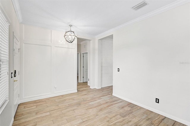 empty room featuring an inviting chandelier, light hardwood / wood-style flooring, and crown molding