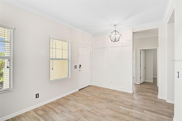 empty room featuring a chandelier, light hardwood / wood-style flooring, and ornamental molding