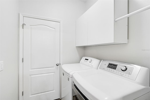 clothes washing area featuring cabinets and washing machine and clothes dryer