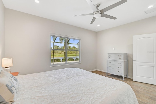 bedroom with ceiling fan, light hardwood / wood-style flooring, and a water view