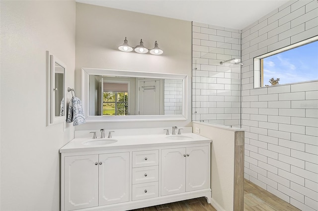 bathroom with hardwood / wood-style flooring, vanity, and tiled shower