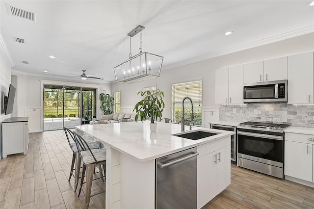 kitchen featuring a center island with sink, stainless steel appliances, a healthy amount of sunlight, and sink