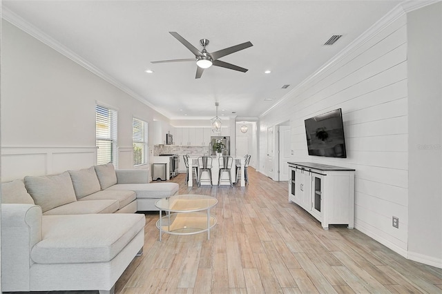 living room featuring light hardwood / wood-style flooring, ceiling fan, and ornamental molding