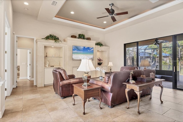 living room with ceiling fan, light tile patterned flooring, built in features, and a tray ceiling