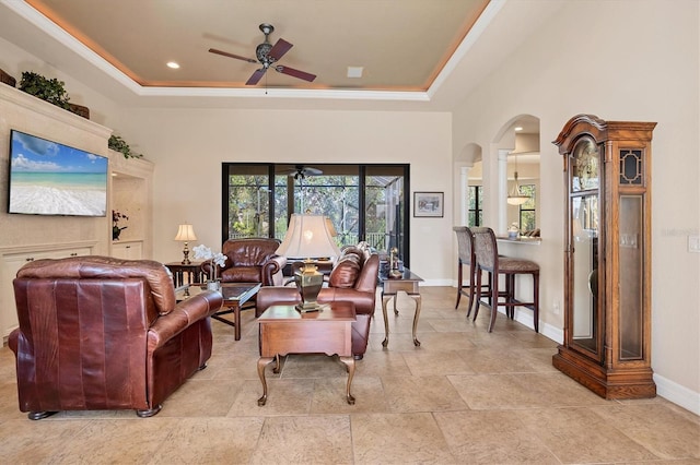 living room with a tray ceiling and ceiling fan