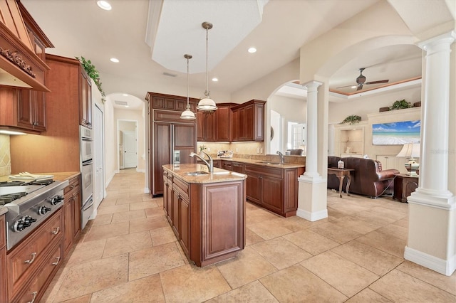 kitchen with a center island with sink, ceiling fan, sink, and hanging light fixtures