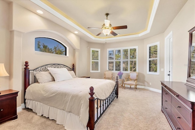 bedroom featuring a raised ceiling, ceiling fan, and light carpet