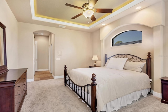 bedroom featuring ceiling fan, a raised ceiling, and light carpet