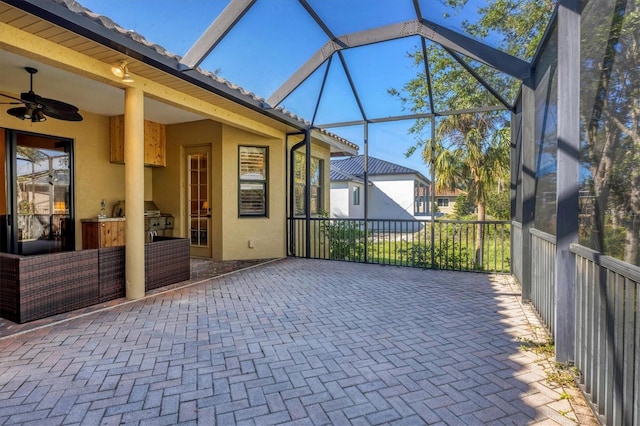 view of patio / terrace with a lanai, grilling area, ceiling fan, and an outdoor kitchen